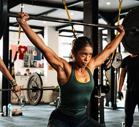 female gym members doing crossfit activities with barbell