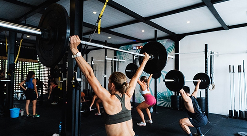 a class of gym goers lifting barbells in barbell club